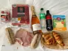 Denne handlekurven kostet kr 161,82 med dagens kurs på 11,34, og inneholder: 1 flaske Codorniu Cava Rosé, 1 Cola Zero, 1 Sprite, 1 pakke Serranoskinke, 1 eske Cherrytomater, 2 grove baguetter, 2 croissanter, 1 pakke skivet Goudaost, 1 pakke Zerranoskinke, og 10 store skiver fersk skinke.