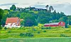 Øyna Kulturlandskapshotellet ligger høyt i terrenget på Inderøy - med utsikt utover Trondheimsfjorden. I forgrunnen gamle Sakshaug kirke, en steinkirke fra 1100-tallet.