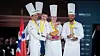 Det norske laget som vant sølv i Bocuse d'Or Europe 2026. Til høyre kandidat Christian A. Pettersen, som har commis Hanna Korvald ved sin side. Til venstre Filip August Bendi. Bak skimtes Ørjan Johannessen.
