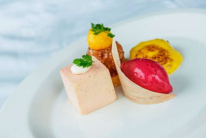Hvit sjokolademousse med fersken, lun mandelkake, capovilla, sabayonne og rød ferskensorbet. (Foto: NKL) Hvit sjokolademousse med fersken, lun mandelkake, capovilla, sabayonne og rød ferskensorbet. (Foto: NKL)
