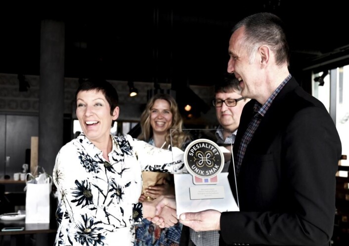 Fagsjef Spesialitet (Matmerk), Marit Strand, tildeler Halvor Hansen Spesialitet-merket for hans boknafisk. I bakgrunnen Liv Margrethe og Viggo Valle. (Foto: Maren Nordtorp Larsen/Matmerk) Fagsjef Spesialitet (Matmerk), Marit Strand, tildeler Halvor Hansen Spesialitet-merket for hans boknafisk. I bakgrunnen Liv Margrethe og Viggo Valle. (Foto: Maren Nordtorp Larsen/Matmerk)