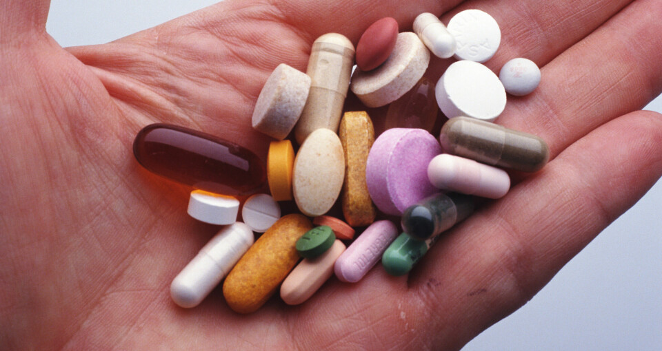 Hånd med ulike piller i mange farger.