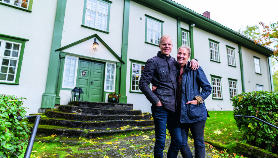 Christian Fredrik og Sabine Sandberg Hoel foran hovedbygningen på Hoel Gård, hvit panel med grønn staffasje.
