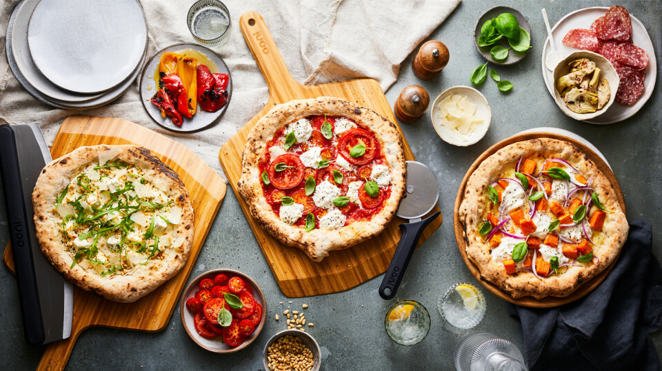 tre ulike pizzaer sett fra fugleperspektiv, fargerikt tilbehør rundt om på bordet.